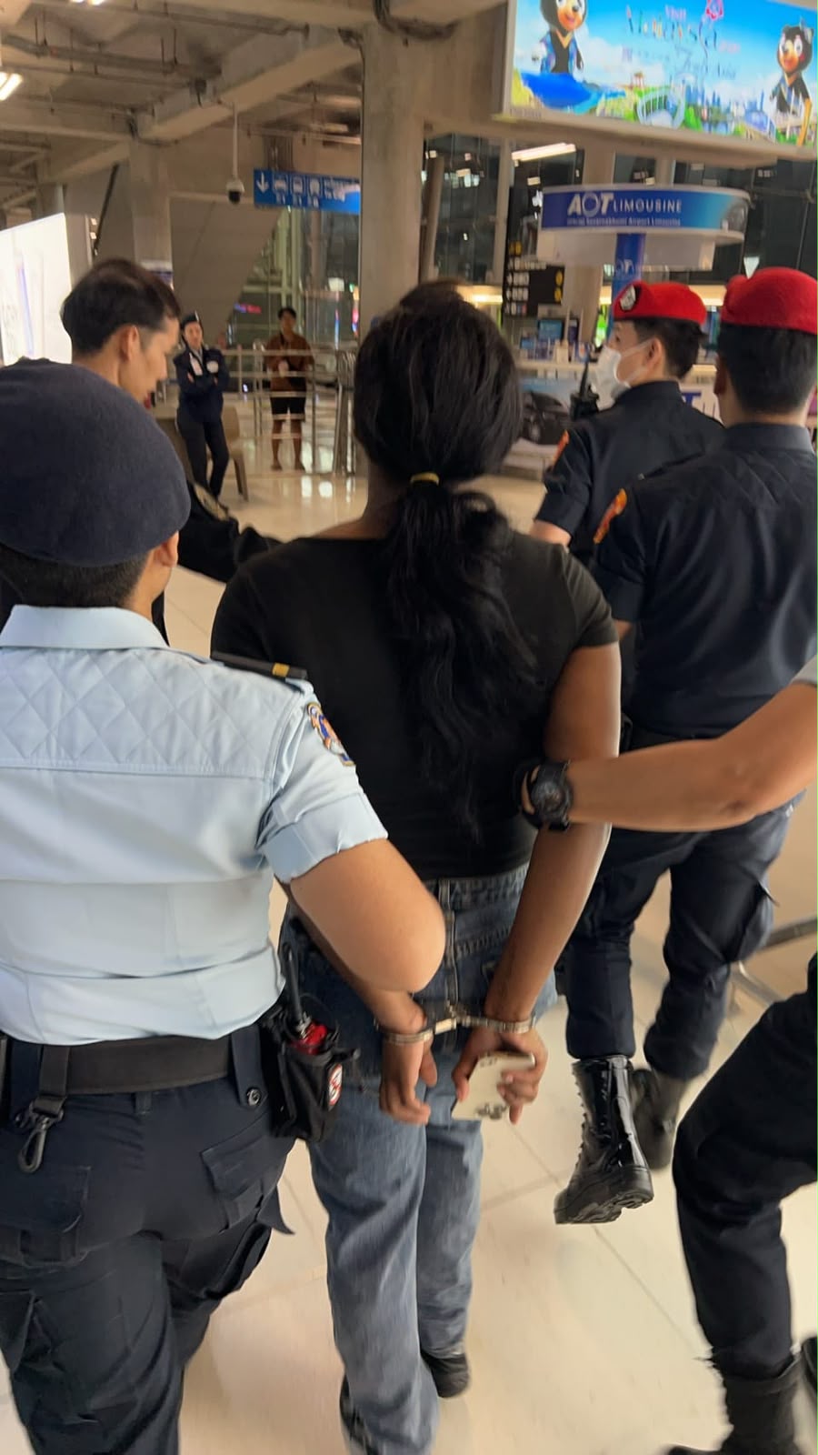 female suspect in handcuffs being escorted by Thai police