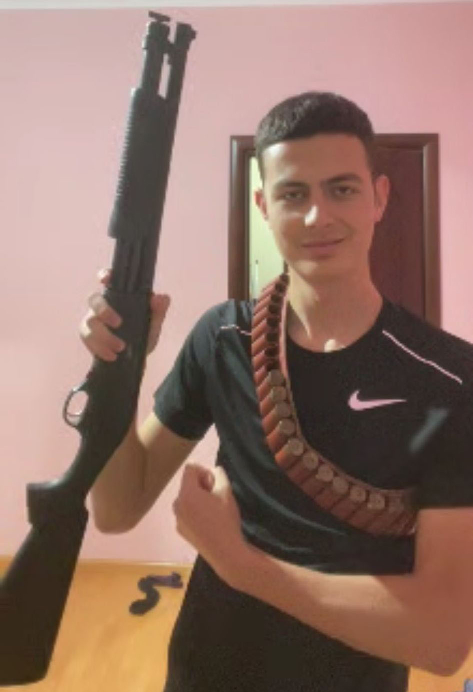 Nikolli holding a firearm