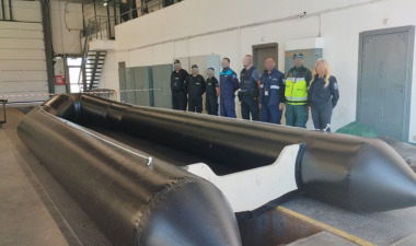 Officers from different agencies standing behind a seized inflated small boat