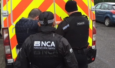 two officers arresting suspect next to police van